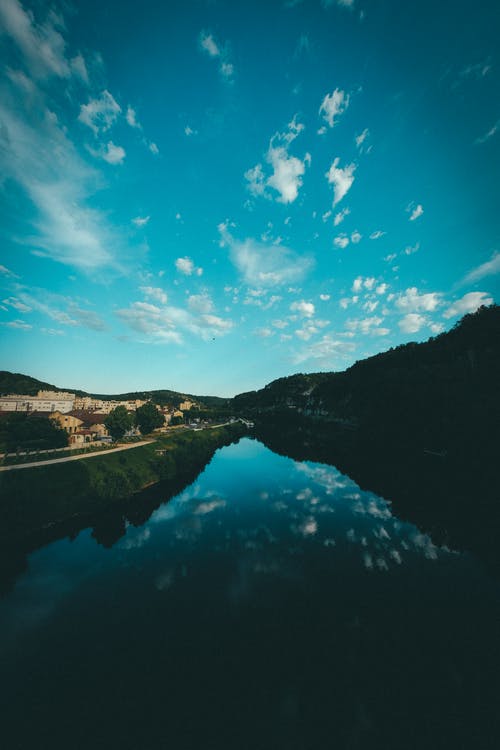 反映在河面上的蓝色和白色的天空 · 免费素材图片