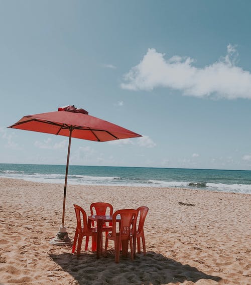 空的红色桌子和椅子在海滩上的伞的选择性聚焦照片 · 免费素材图片