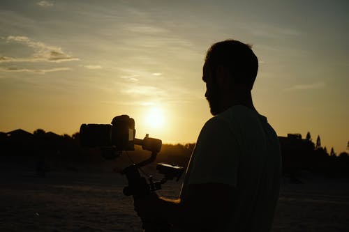 男子在黄金时段手持相机的剪影照片 · 免费素材图片