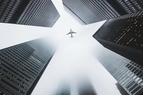 飞机飞越高层建筑的低角度照片 · 免费素材图片