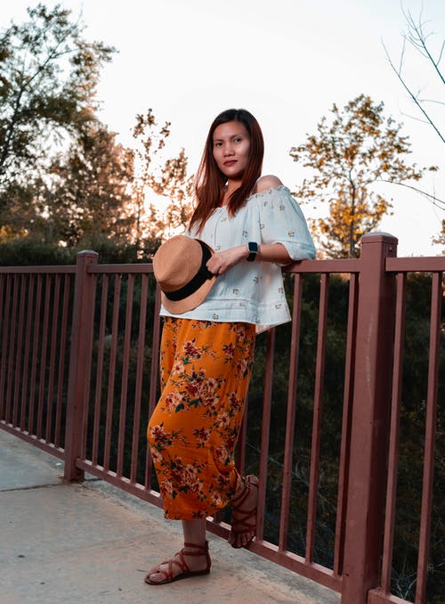 女人穿着白色的露肩上衣倾斜在扶手上 · 免费素材图片