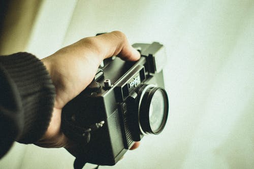 拿着黑柯尼卡c35相机的人的手的特写照片 · 免费素材图片