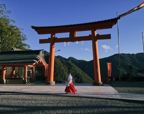 女人穿着红色和白色的裙子，走在神社附近 · 免费素材图片