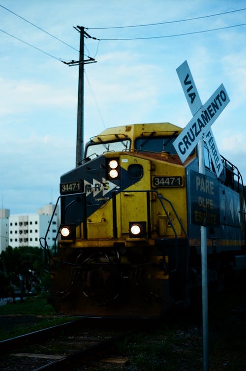 靠近电线杆的钢栏杆上的黄色火车 · 免费素材图片