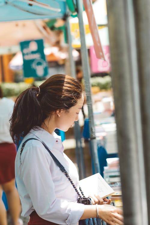 女人拿着本书的照片 · 免费素材图片