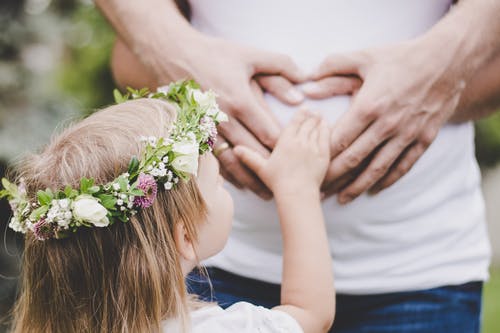 女孩抱着她妈妈的肚子 · 免费素材图片