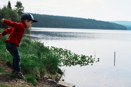 红色夹克的男孩即将在水中跳跃 · 免费素材图片