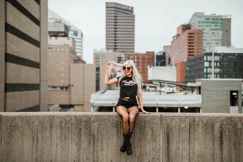 一个女人坐在墙上的照片 · 免费素材图片