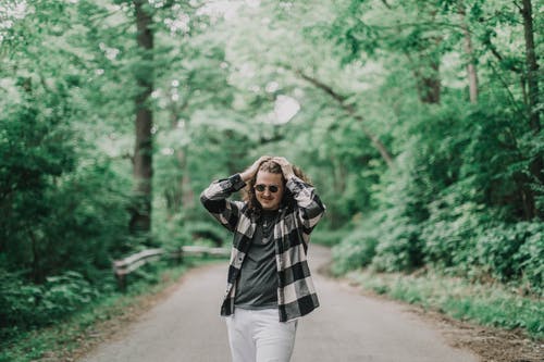 一个人站在树木环绕的道路上的照片 · 免费素材图片