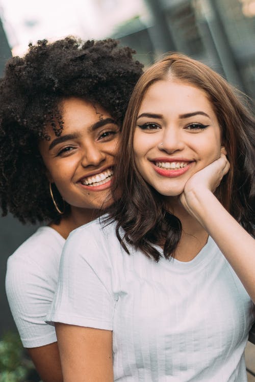 两个女人微笑穿白衬衫的照片 · 免费素材图片