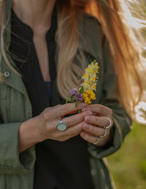 女人拿着黄色的花瓣花的特写照片 · 免费素材图片