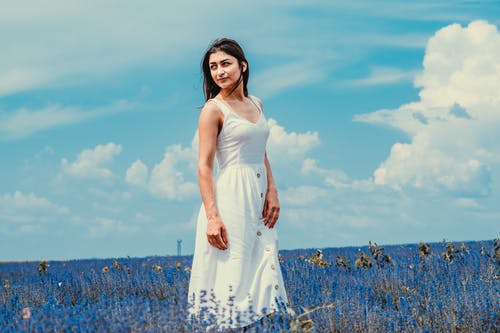 站在蓝色的花场中的白色连衣裙的女人 · 免费素材图片