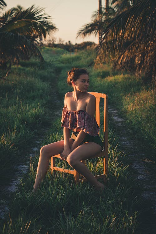 坐在木椅上的女人穿着管女衬衫的照片 · 免费素材图片