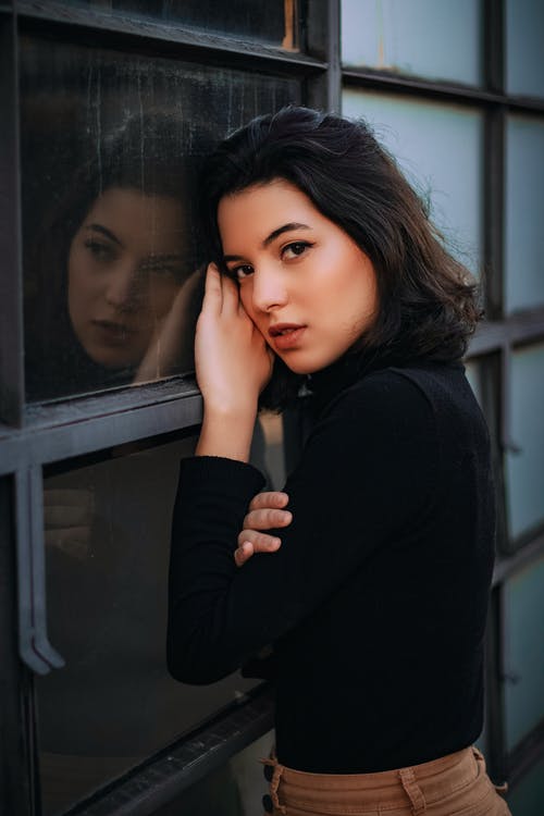 靠在窗户上的女人的照片 · 免费素材图片