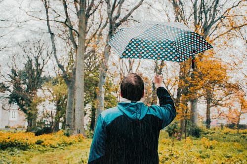 下雨时手持雨伞的男子的照片 · 免费素材图片