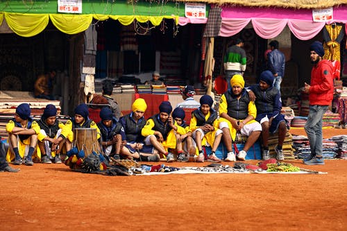 一群男人穿着黑色和黄色的裙子，坐在地板上 · 免费素材图片