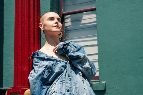 穿蓝色牛仔夹克的女人的照片站立在窗口附近 · 免费素材图片