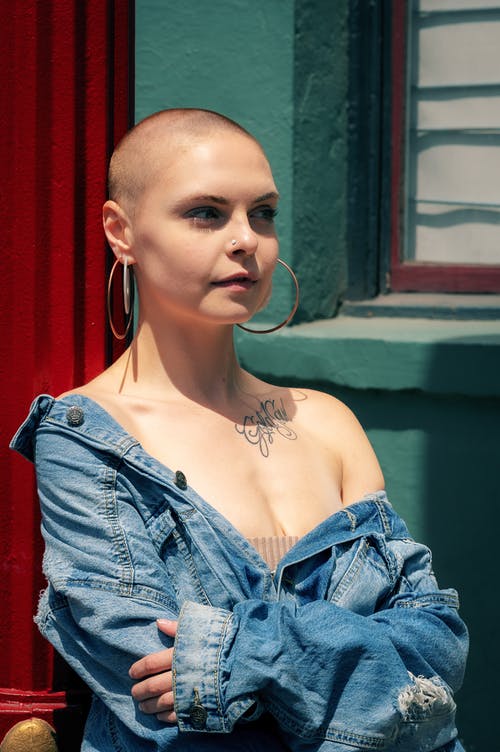 穿蓝色牛仔夹克的女人的照片站立在窗口附近 · 免费素材图片