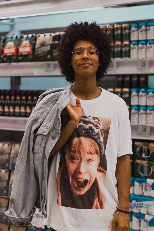 站在超市货架前的男人微笑着的照片 · 免费素材图片