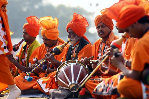 穿着橙色服装的男人玩乐器 · 免费素材图片