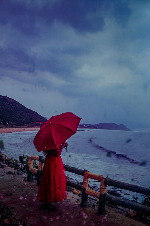 拿着红色的雨伞，穿着红色的衣服的人的照片 · 免费素材图片