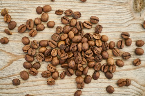 在木质表面上的咖啡豆平躺摄影 · 免费素材图片