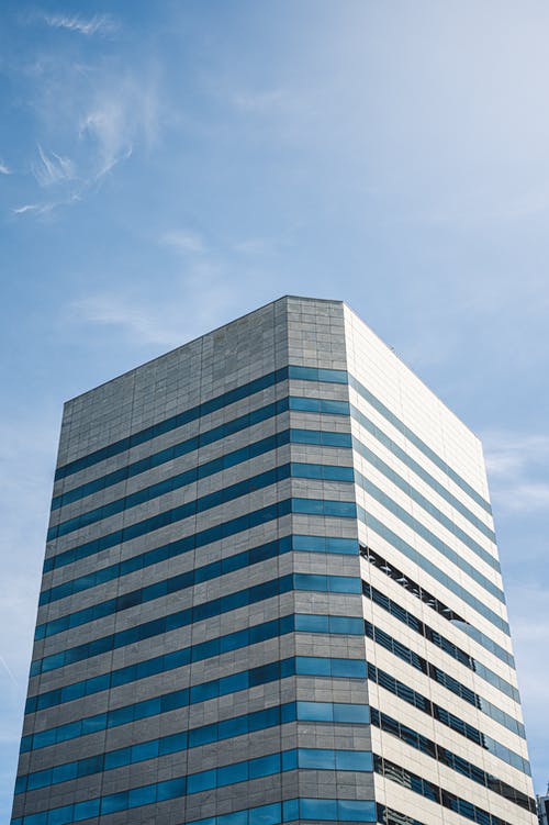 蓝蓝的天空下的灰色高层建筑 · 免费素材图片