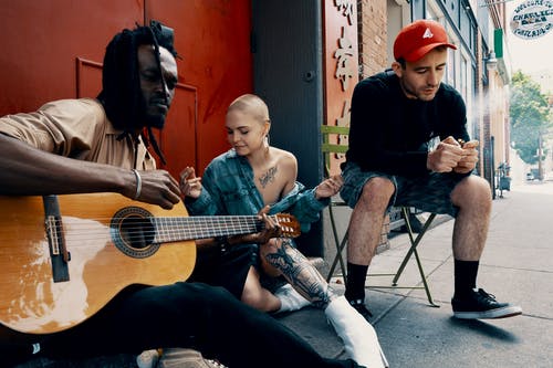男人和女人坐在大街上，弹吉他 · 免费素材图片
