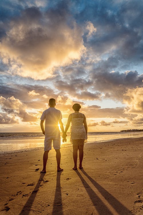 夫妇站在沙滩上看着地平线的背影照片 · 免费素材图片