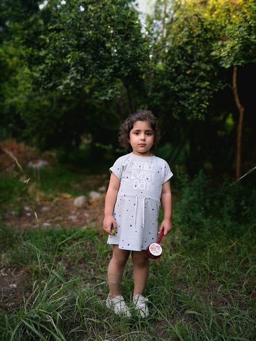 一个小女孩站在树前的照片 · 免费素材图片