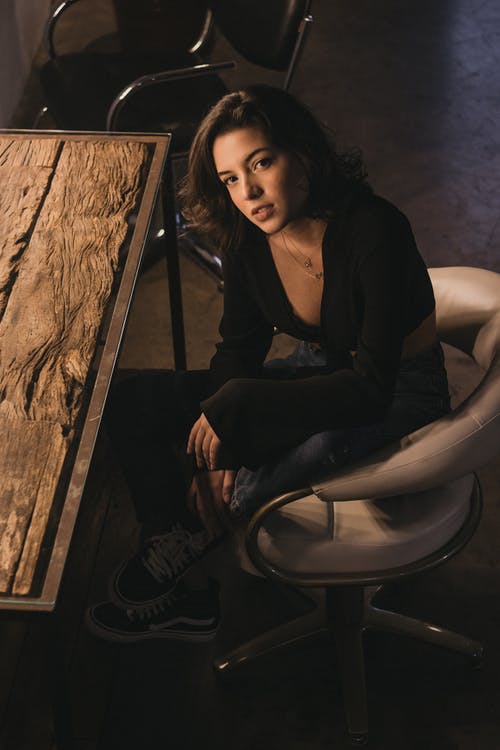 女人坐在木桌旁附近的转椅上的照片 · 免费素材图片