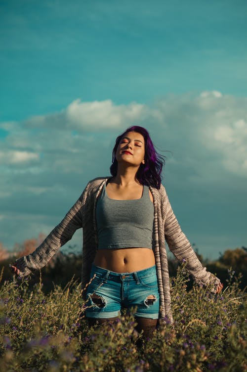 作物顶部和空站在绿色草地上的女人 · 免费素材图片