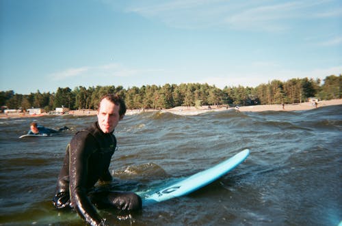在海滩上在他的冲浪板上休息的人 · 免费素材图片
