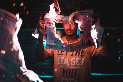 男子手持燃烧的报纸 · 免费素材图片