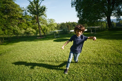 男孩在绿色草地上运行 · 免费素材图片