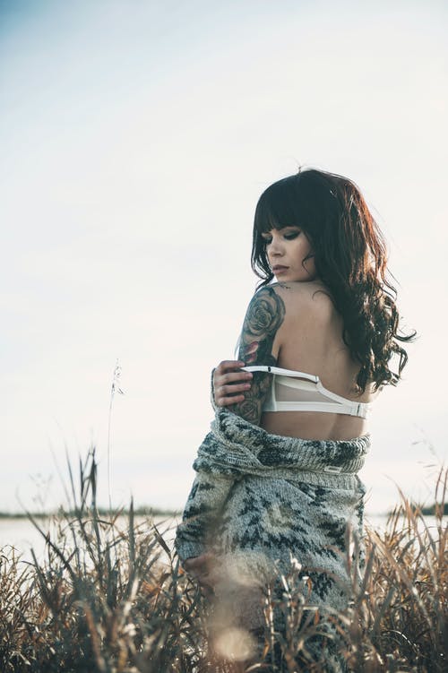 水旁草丛构成的灰色毛衣和白色胸罩纹身女人的照片 · 免费素材图片