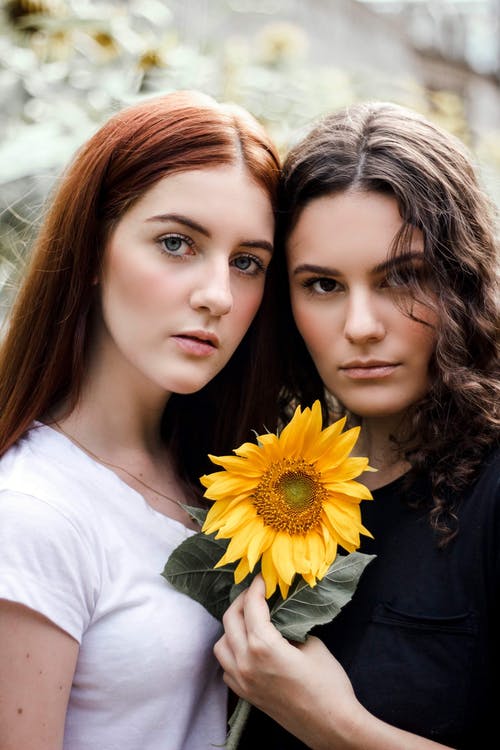 拿着黄色花的两名妇女的照片 · 免费素材图片