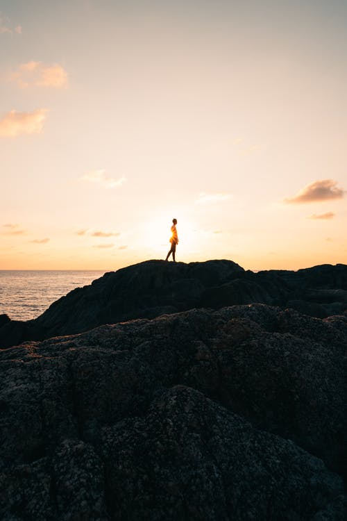 站在岩石山面对大海的人 · 免费素材图片