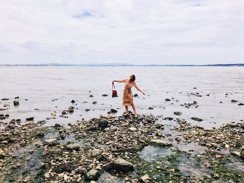 站在多岩石的海滨上一个女人的照片 · 免费素材图片