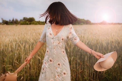 多彩多姿的花裙子，站在农作物中间拿着草帽的女人 · 免费素材图片