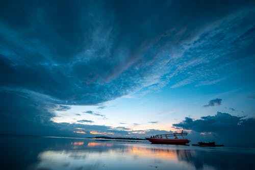 小船在平静的水体在蓝蓝的天空下的照片 · 免费素材图片
