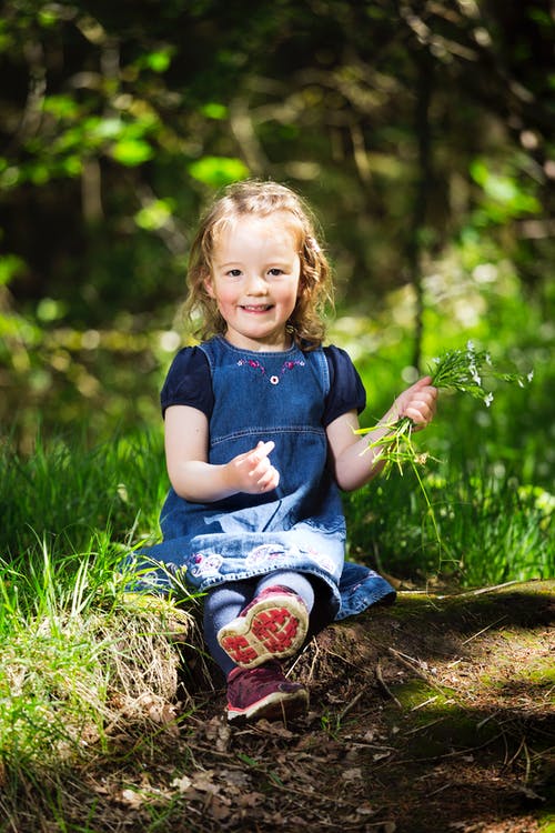 一个小女孩坐在草地上的照片 · 免费素材图片