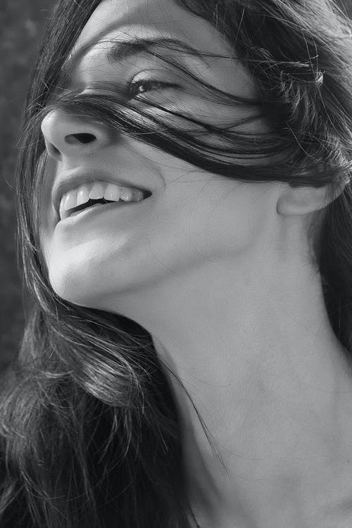 微笑的女人的脸的灰度特写照片 · 免费素材图片