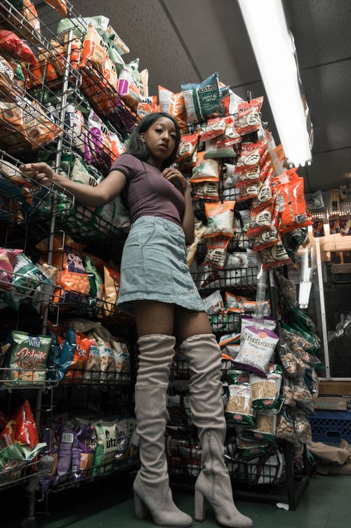 女人站在一家商店的架子旁边 · 免费素材图片