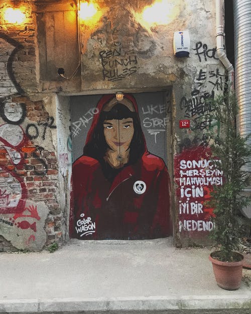 女人穿着连帽的夹克绘画在闭着的门上显示点燃户外灯 · 免费素材图片