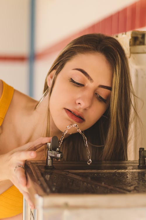 女人在饮水机上喝水的特写照片 · 免费素材图片