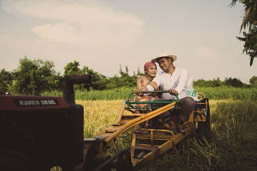 一对夫妇骑在拖拉机上的照片 · 免费素材图片