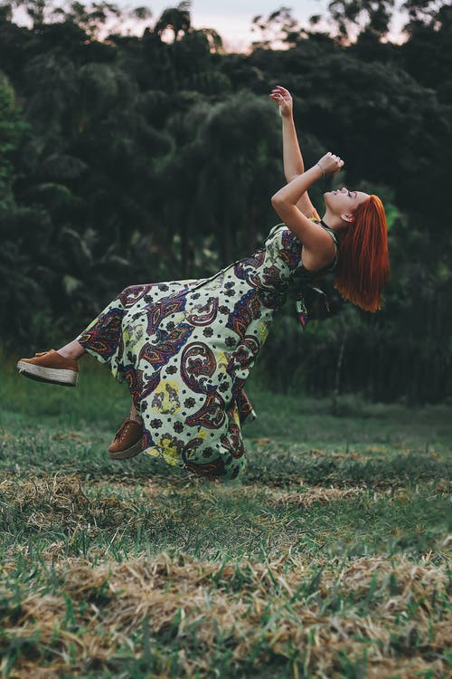 女人在草地上跳跃的延时摄影 · 免费素材图片