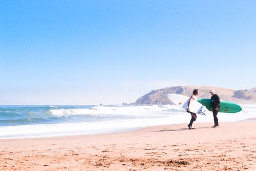两名男子站在海滩上携带冲浪板的照片 · 免费素材图片