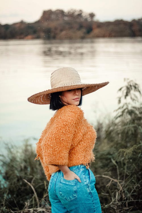 太阳帽，橙色针织上衣和蓝色牛仔下装的女人的照片 · 免费素材图片